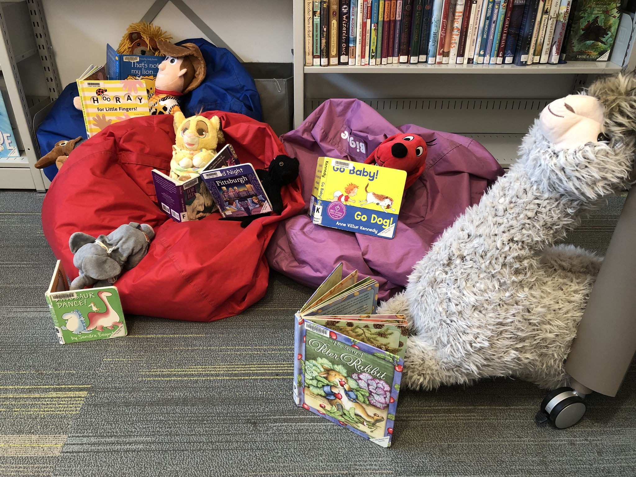 Stuffed animals posed reading books