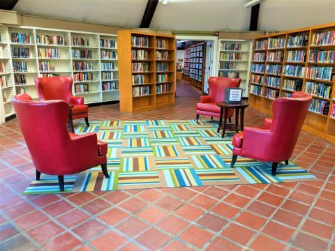 Room with four armchairs, a rug and shelves of books.