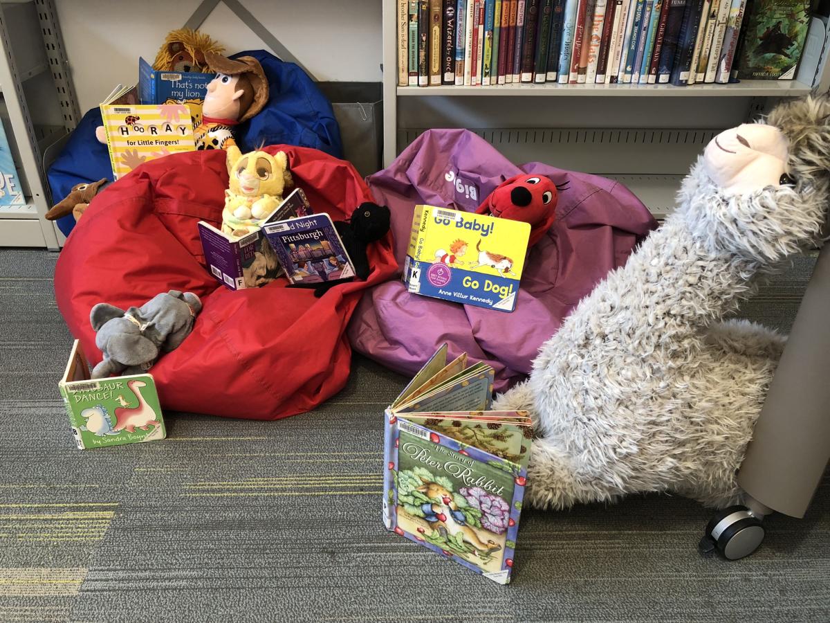 Stuffed animals posed reading books